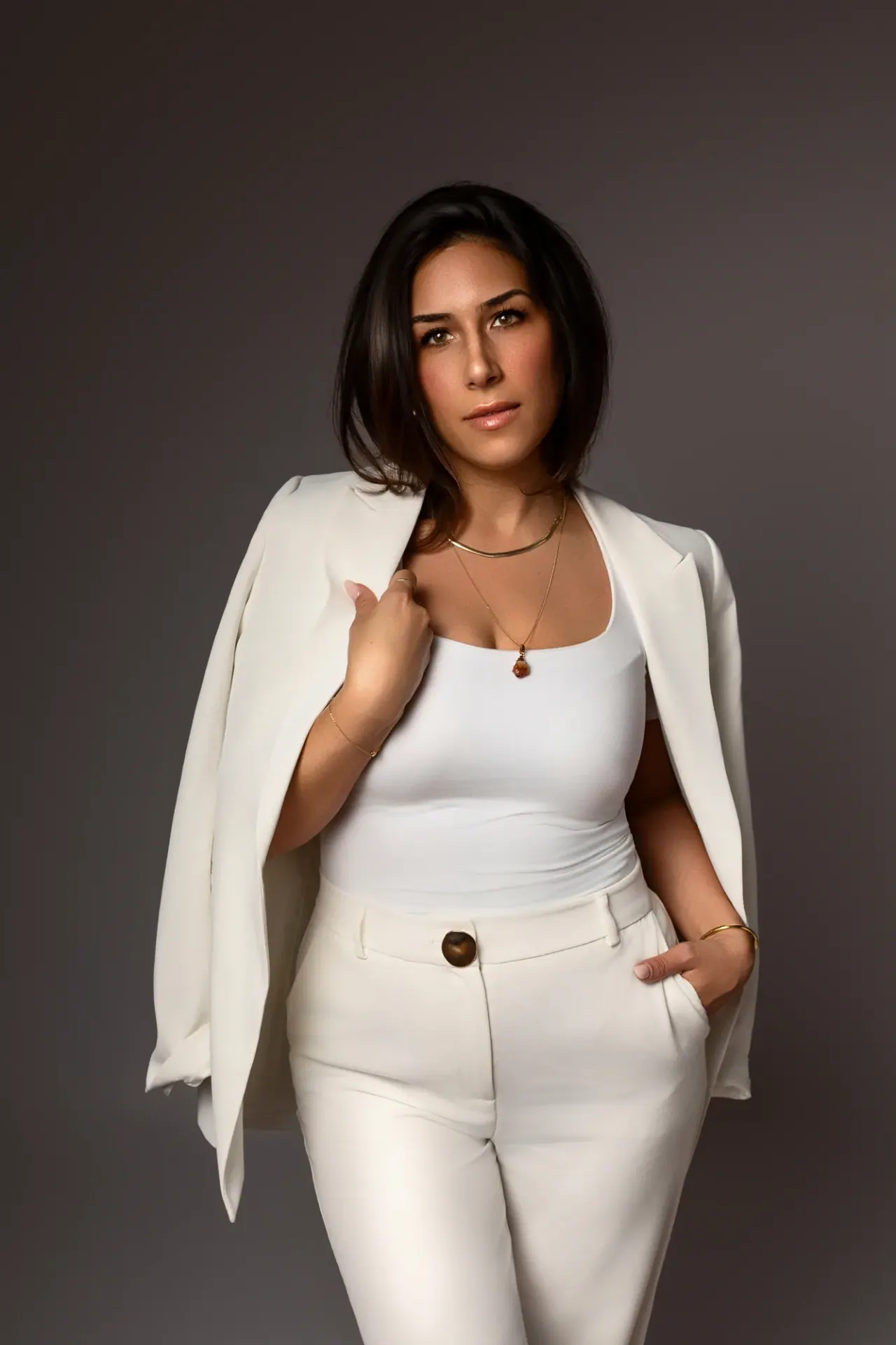 Merve Durmus im weißen Blazer vor grauem Hintergrund