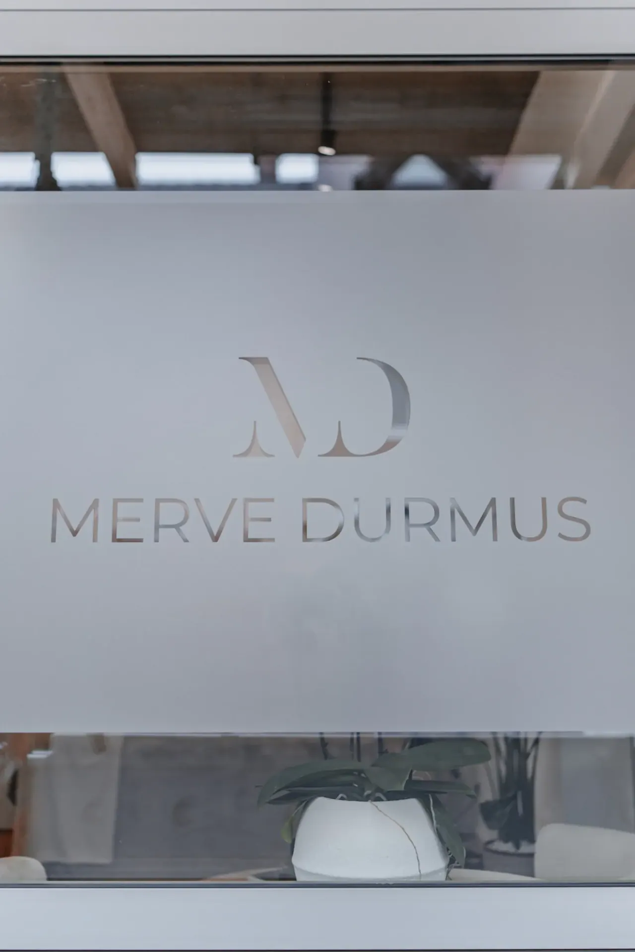 Glasfläche mit dem Logo Merve Durmus am Eingang des Studios